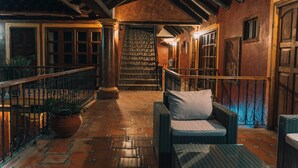 A cozy interior with a staircase, wicker furniture, and a tiled floor.
