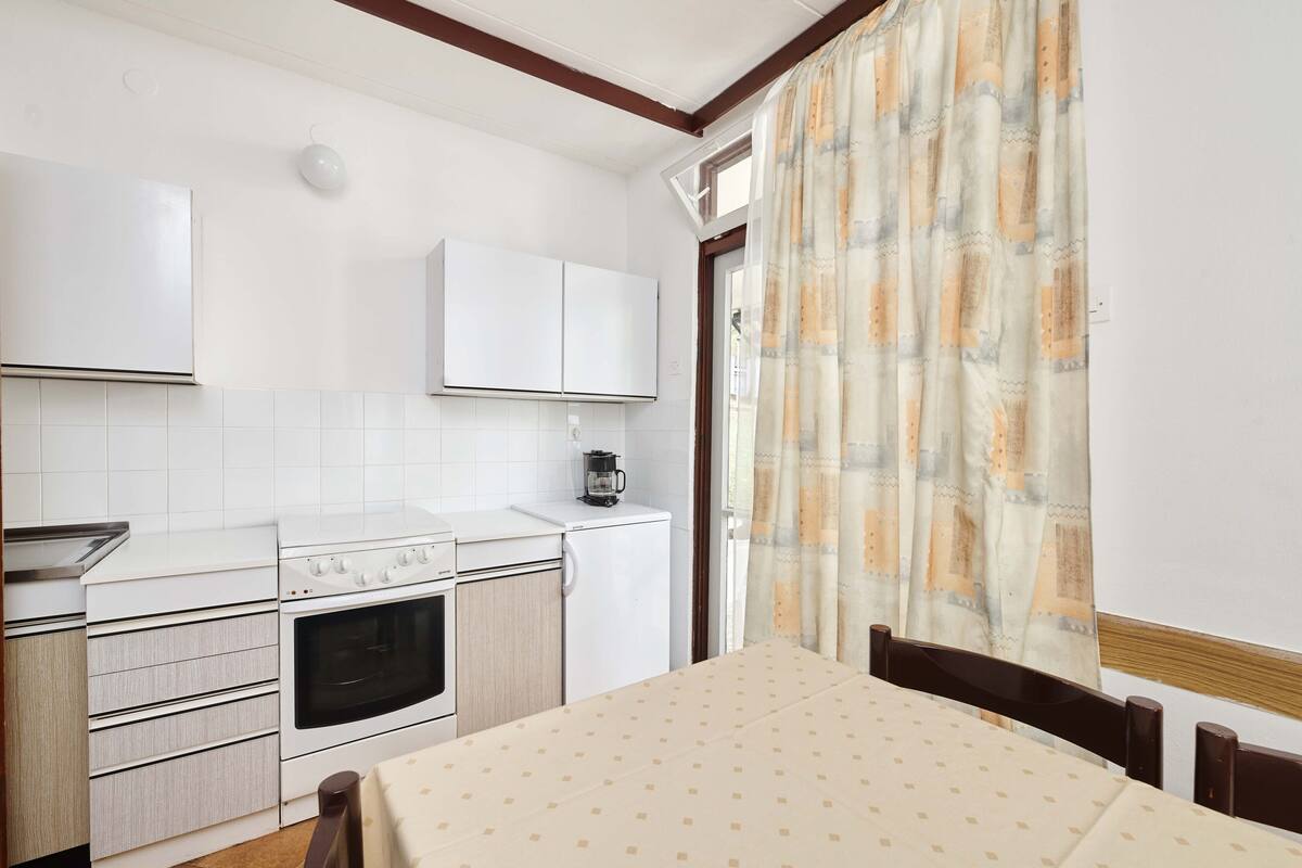 A compact kitchen with white cabinetry, a stove, oven, and a small refrigerator.