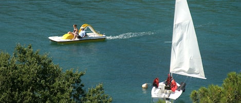 A boat with a sail and a motorboat with two people.