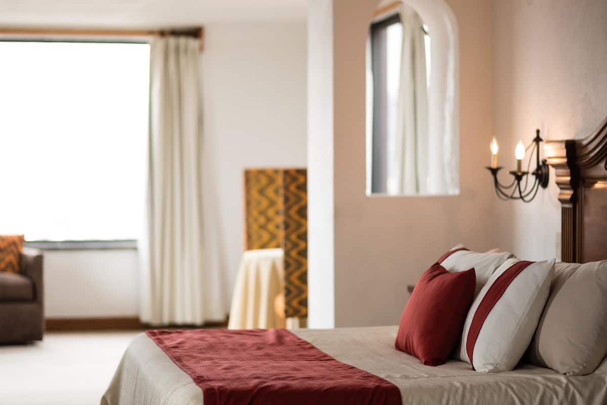 Una habitación de hotel con cama, ventana, silla y mesa.