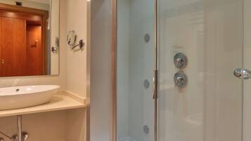 A modern bathroom with a glass-enclosed shower, a sink, and a mirror.