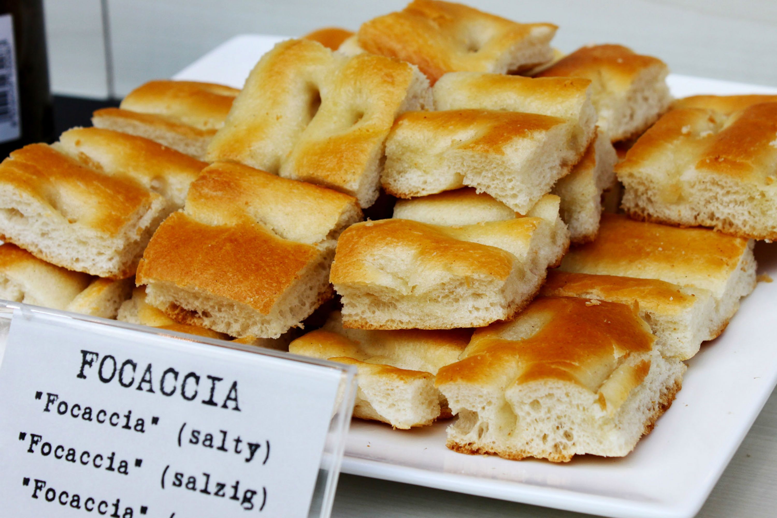 Une assiette de pain focaccia avec un panneau indiquant qu’il est salé.