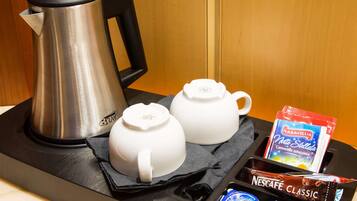 A tray with a coffee maker, two white teapots, a box of Nescafe Classic, and two packets of Sturmer coffee.