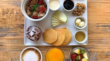 A breakfast tray with pancakes, a muffin, fruit, and beverages.