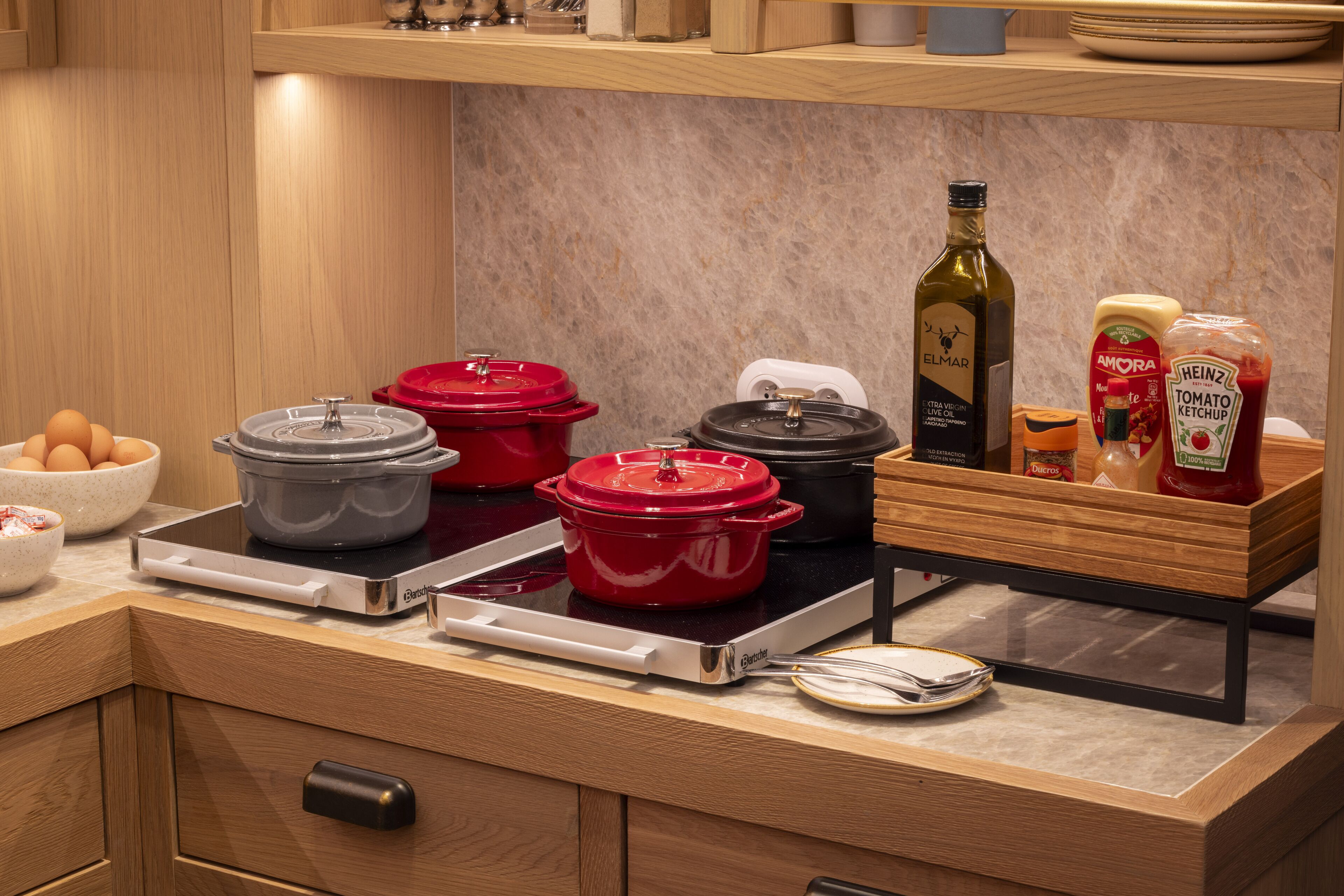 A kitchen with a stove, pots, a bottle of olive oil, and condiments.