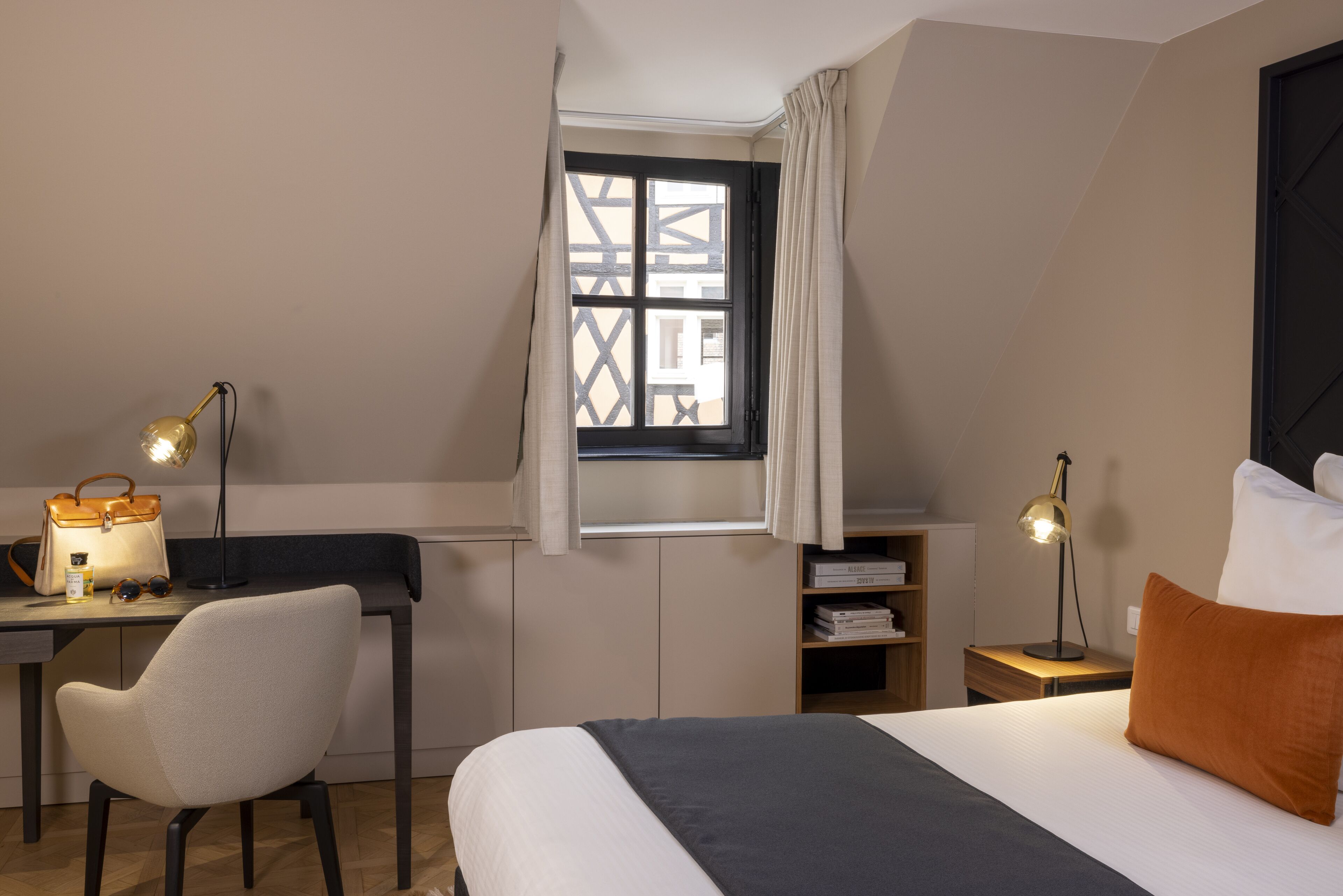 A bedroom with a bed, desk, chair, and nightstand with lamps.