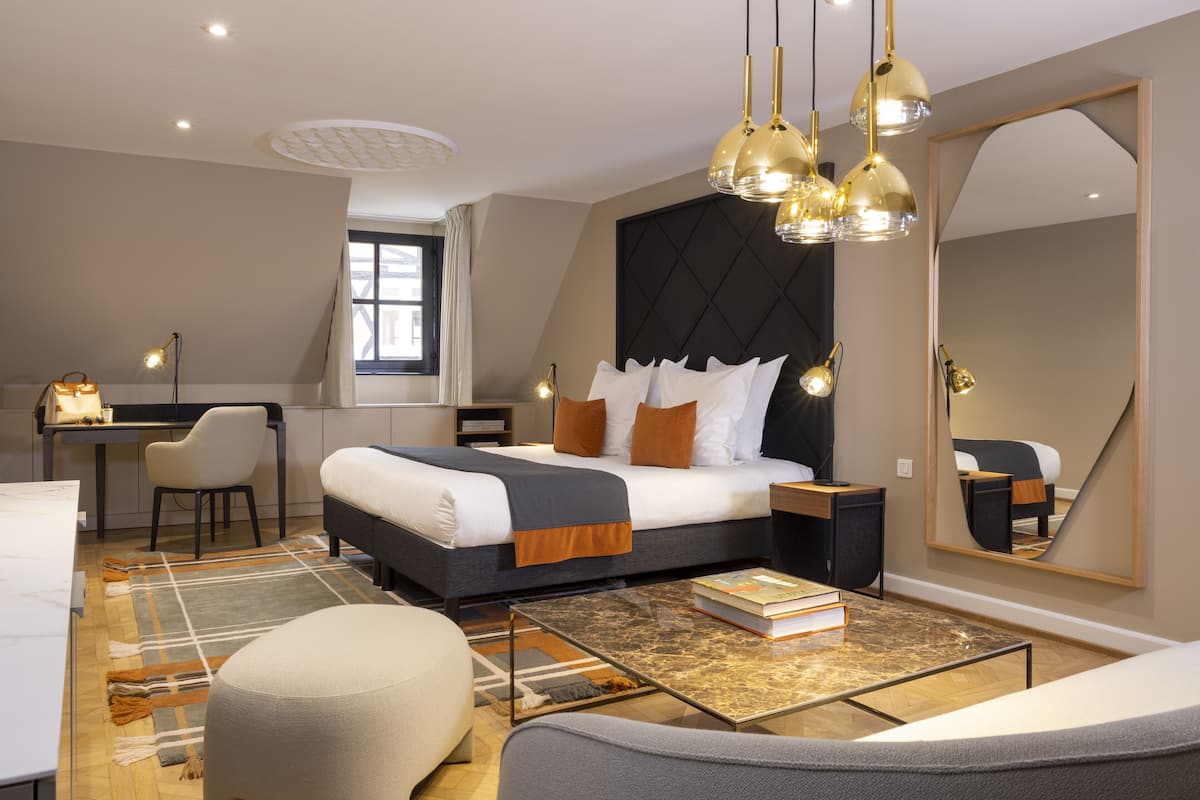 Moderni hotellihuone, jossa on suuri sänky, työpöytä, tuoli ja iso peili.