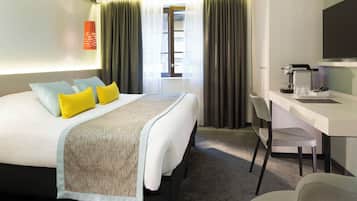 A hotel room with a bed, a desk, a chair, a television, and a window with curtains.