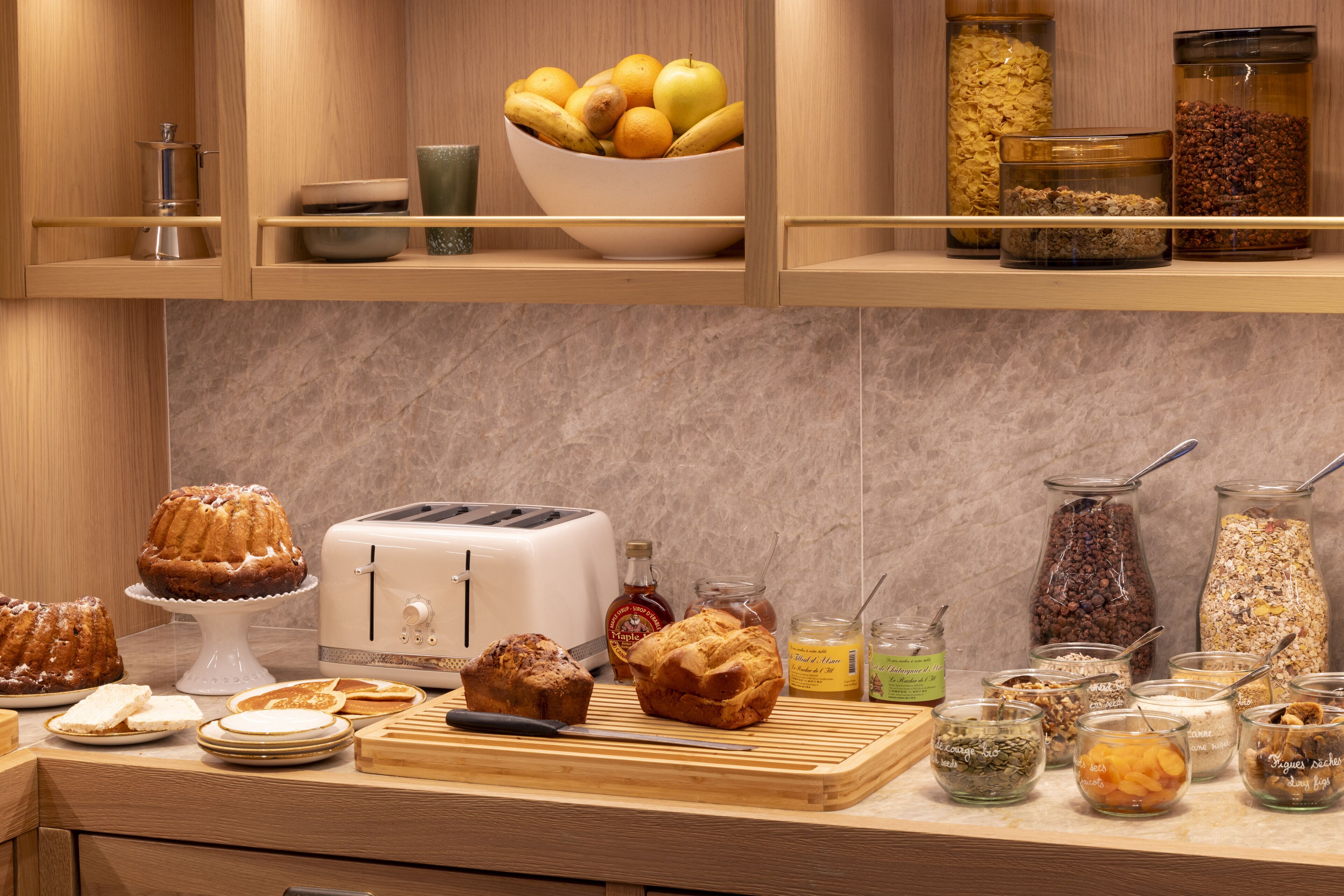 A kitchen with a toaster, various baked goods, and jars of ingredients.