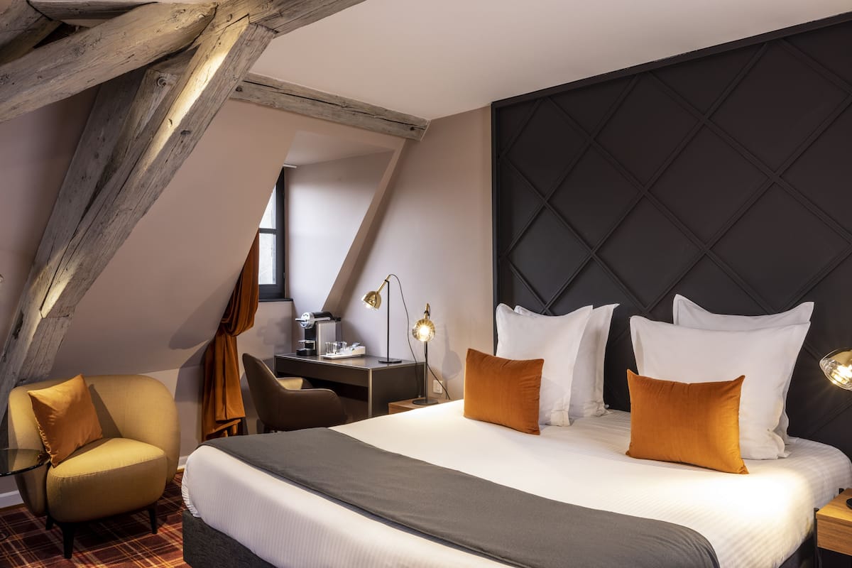 Hotellihuone, jossa on suuri sänky, työpöytä, tuoli ja ikkuna.