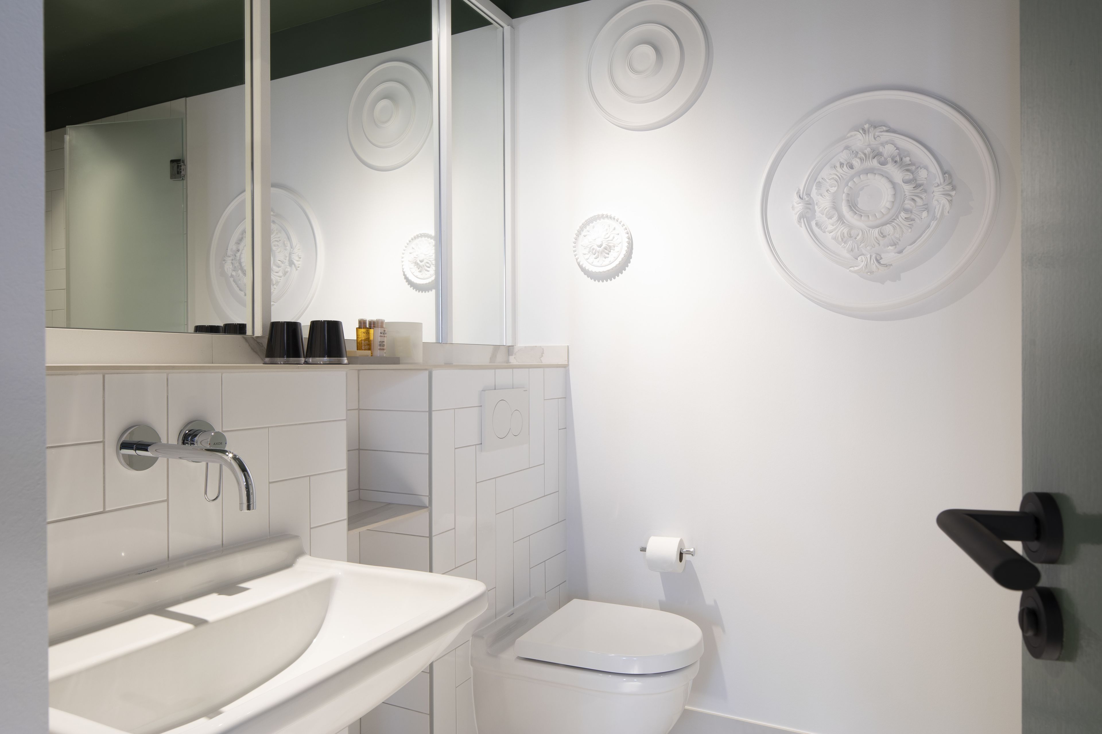 A modern bathroom with a white sink, a toilet, and decorative wall panels.