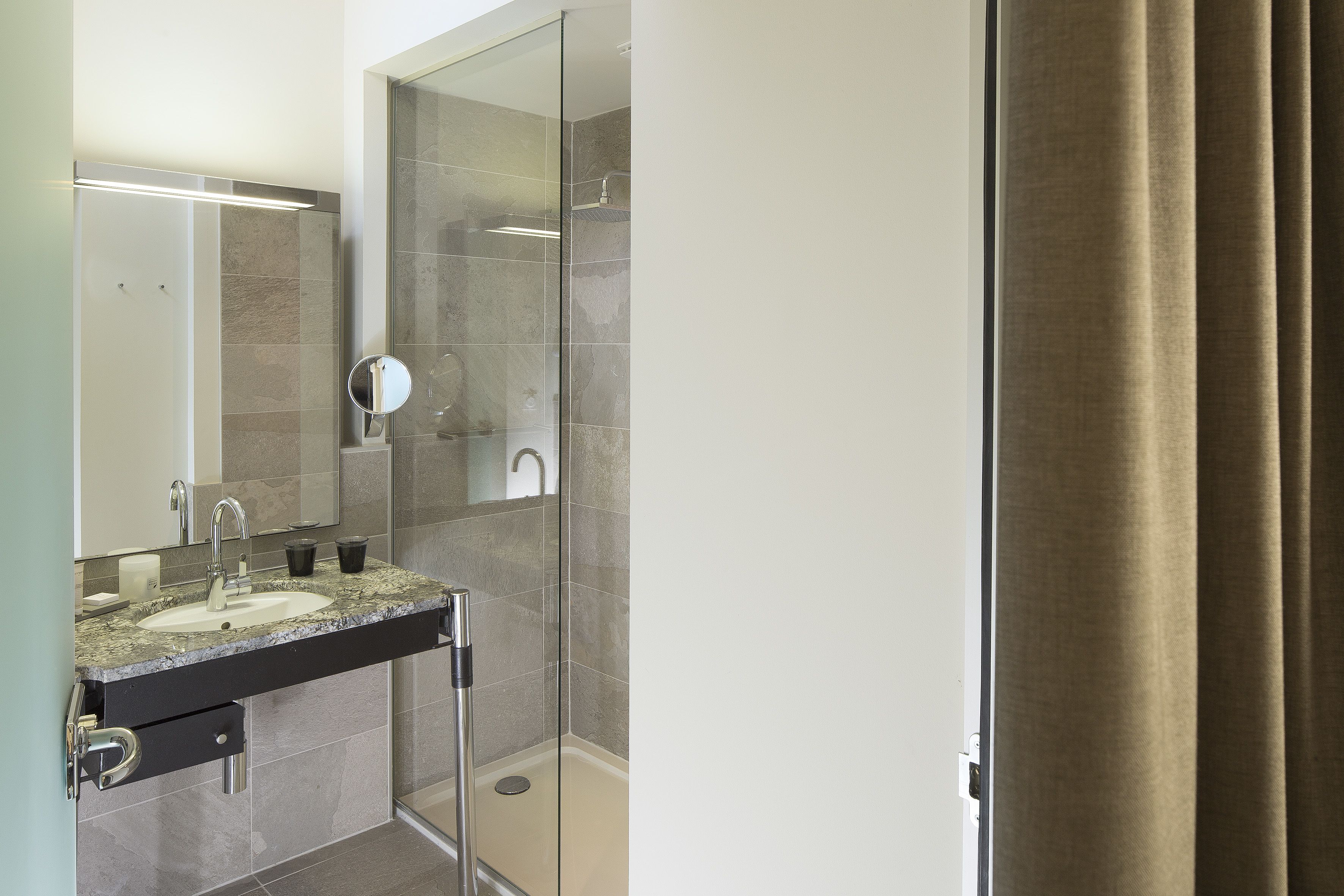 Une salle de bain moderne avec une douche à parois de verre, un lavabo avec un miroir et un porte-serviettes.