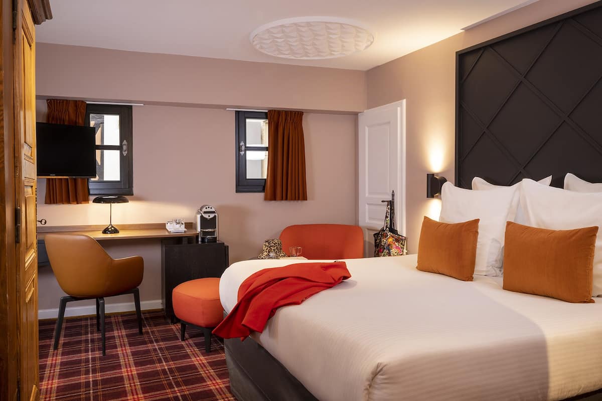 Hotellihuone, jossa on sänky, työpöytä, tuoli ja televisio.