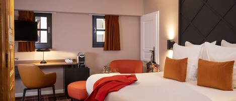 A hotel room with a bed, a desk, a chair, and a television.