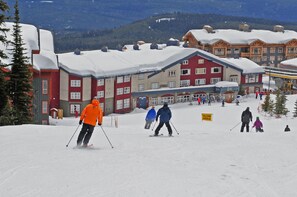 A ski resort with a row of multi-story buildings, ski slopes, and a 'SLOW AREA' sign. - White Crystal Inn (Beaverdell)