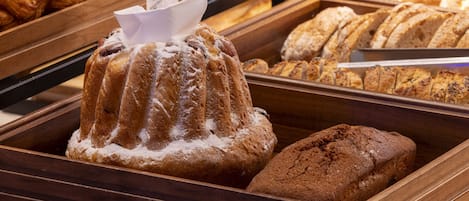 A bakery display with various baked goods including a bundt cake, sliced bread, and croissants.