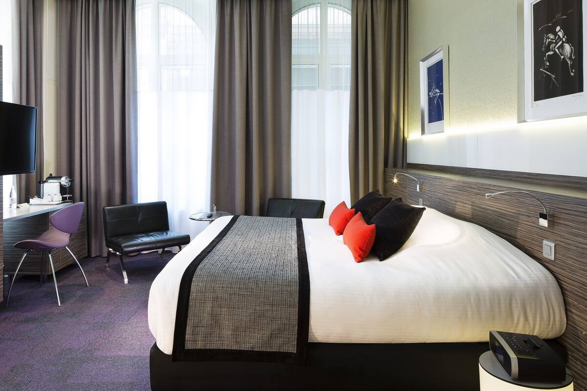 Habitación de hotel con una cama grande, un escritorio con computadora, una silla y un televisor.