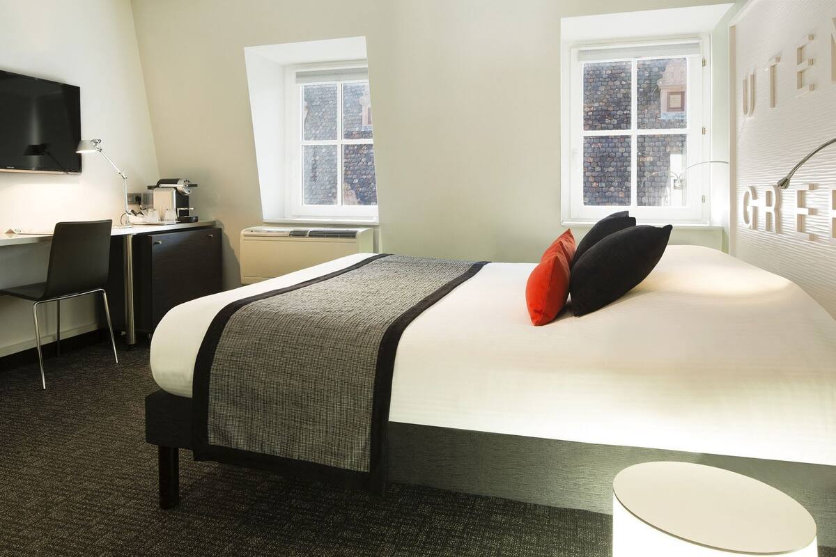 Una habitación de hotel con cama, escritorio, silla y televisor.