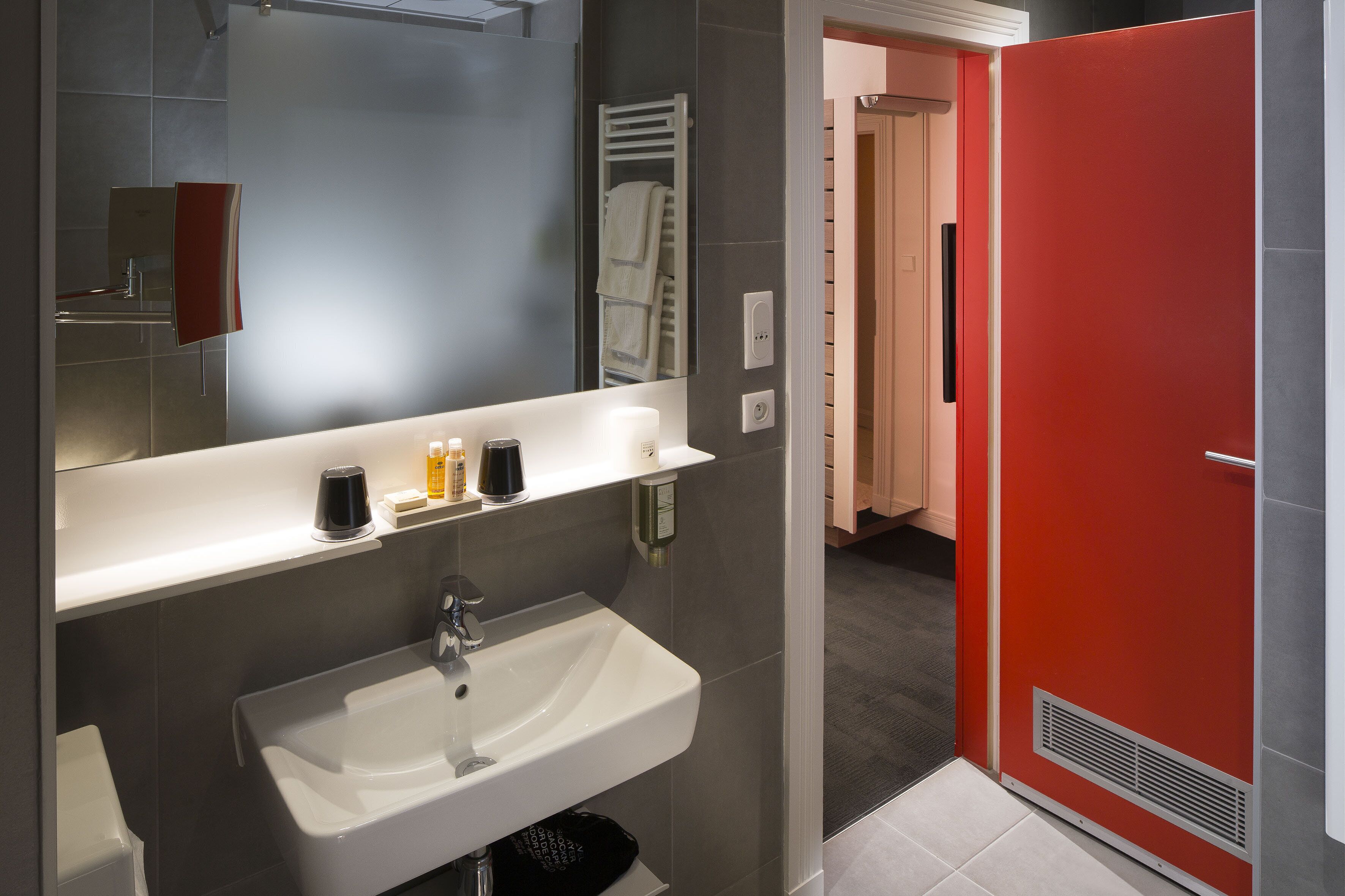 Une salle de bain moderne avec un lavabo blanc, un miroir et un porte-serviettes.