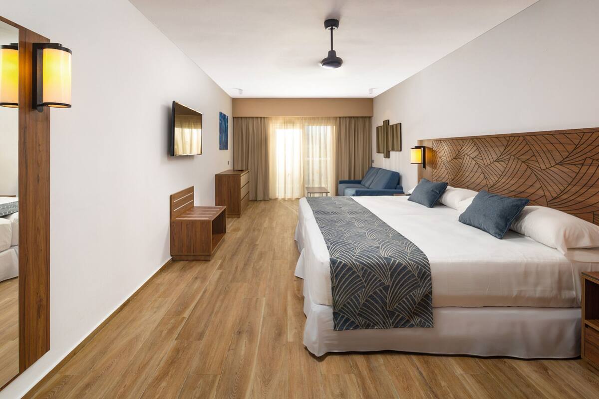 Una habitación de hotel moderna con una cama grande, un escritorio, una silla y un armario.