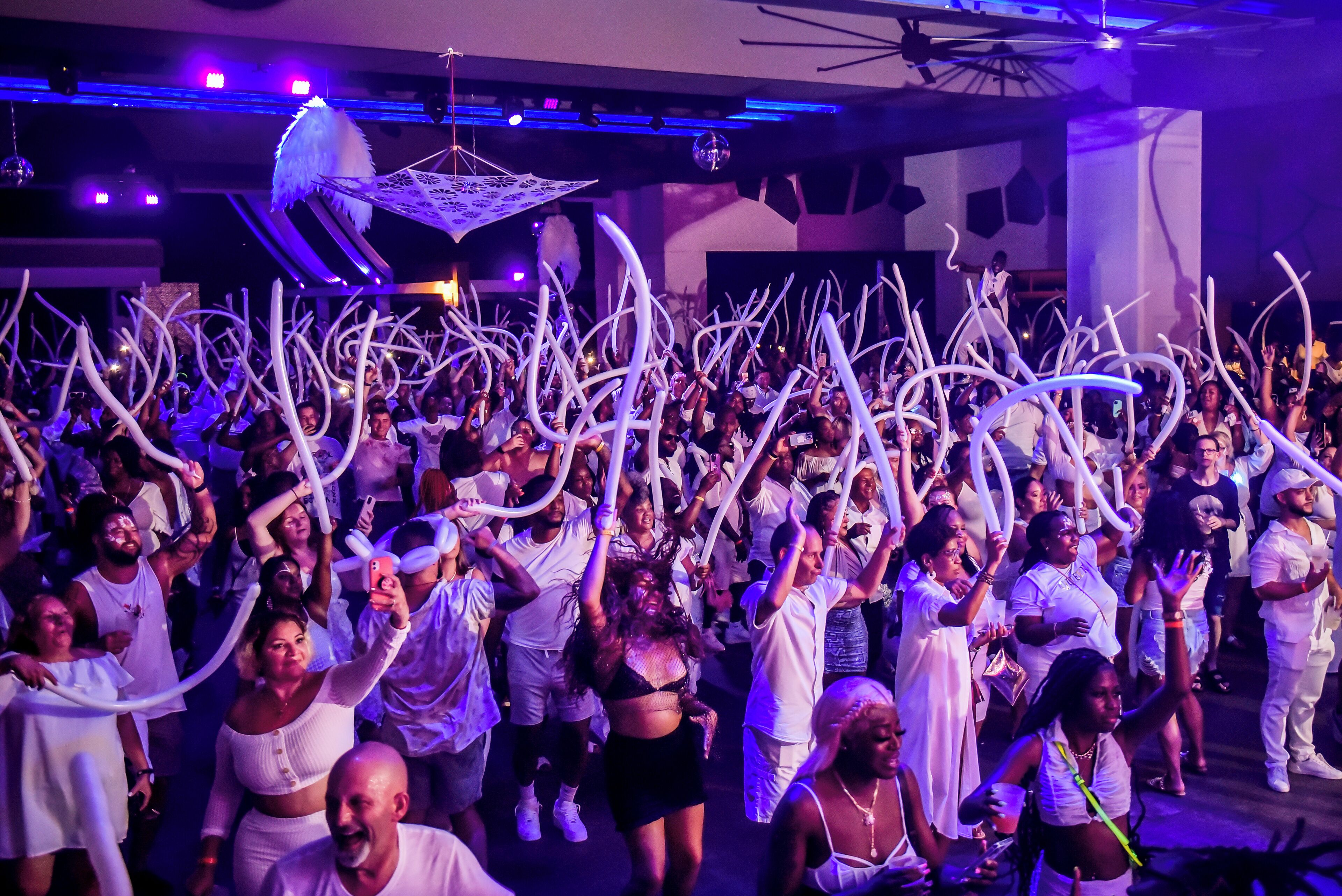 A crowded indoor event with people holding white streamers.