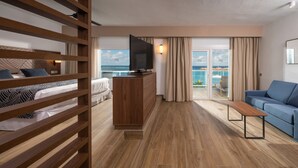 A hotel room with a balcony, wooden furniture, a TV, and a view of the ocean. - Hotel Riu Montego Bay - Adults Only - All Inclusive (Montego Bay)