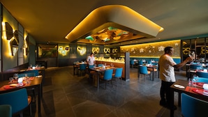 A modern restaurant interior with a bar area, blue chairs, and a chef preparing food. - Hotel Riu Montego Bay - Adults Only - All Inclusive (Montego Bay)
