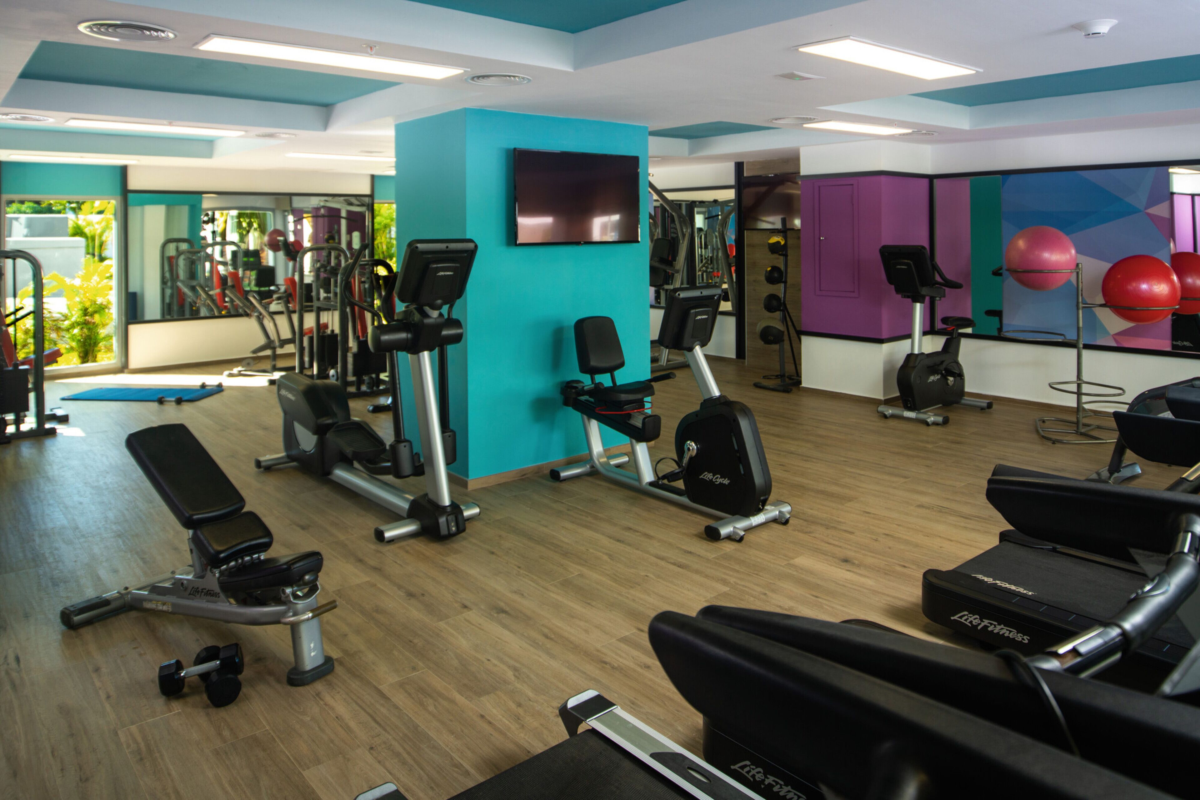 A gym with exercise equipment, a TV, and a mirror.