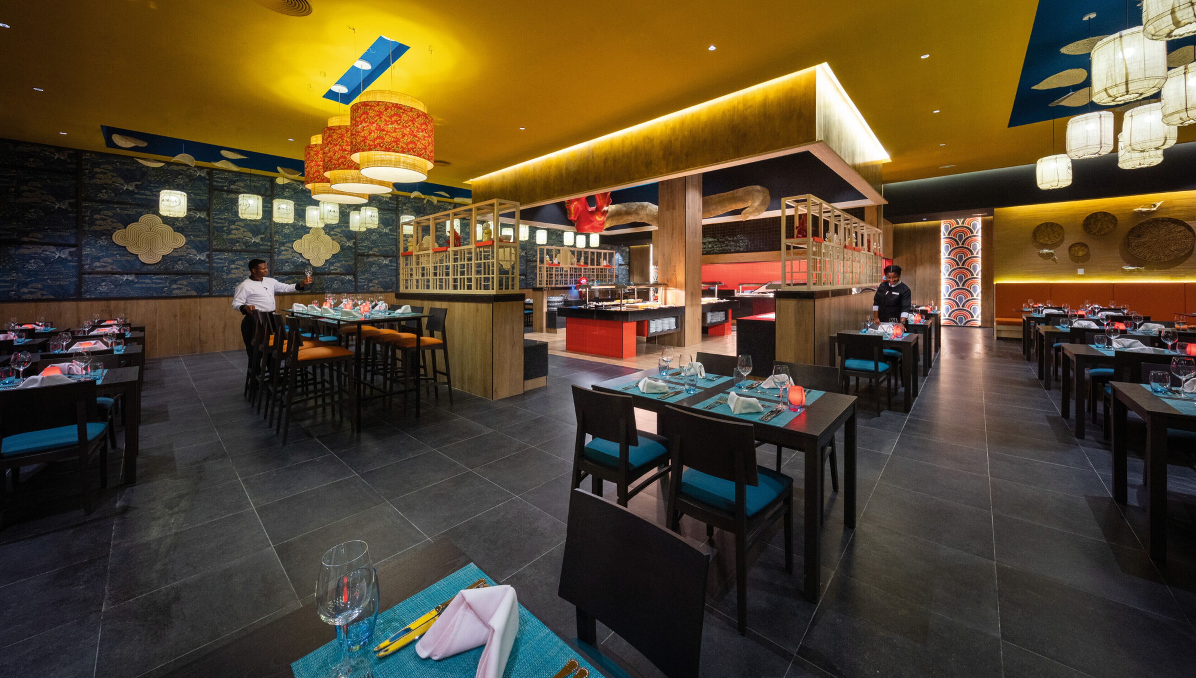 Un ristorante con diversi tavoli, un'area bar e uno chef che cucina.