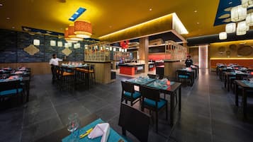 Un ristorante con diversi tavoli, un'area bar e uno chef che cucina.