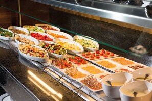 A buffet with various dishes including salads, pasta, and appetizers.