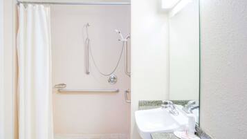 A bathroom with a shower, grab bar, and sink.