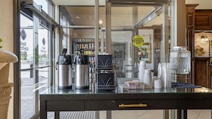 Mostrador de cafetería con una máquina de café, un dispensador de agua caliente y una prensa francesa.