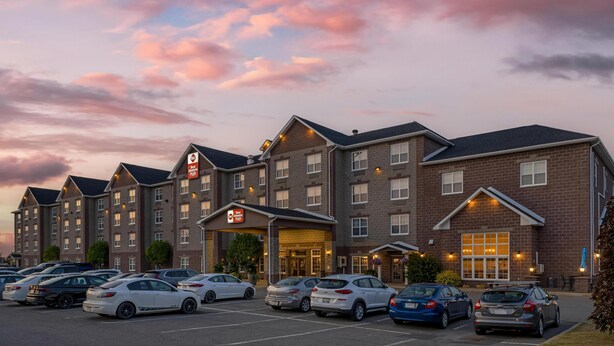 Un hotel con varias edificaciones, un estacionamiento y automóviles.