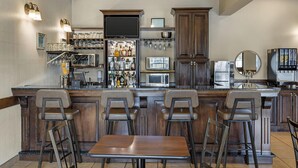 Una cocina con barra, equipada con microondas, refrigerador y diversos electrodomésticos.
