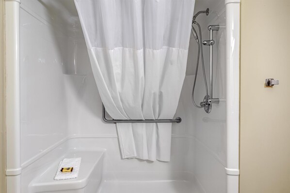 Ducha con cortina blanca, cabezal de ducha de mano y un perchero para toallas.