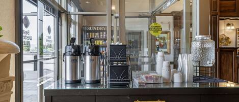 A coffee shop counter with a coffee machine, a hot water dispenser, and a coffee press.