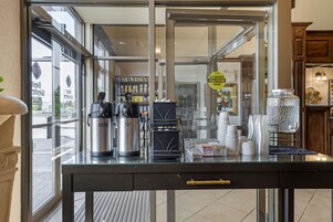 A coffee shop counter with a coffee machine, a hot water dispenser, and a coffee press.