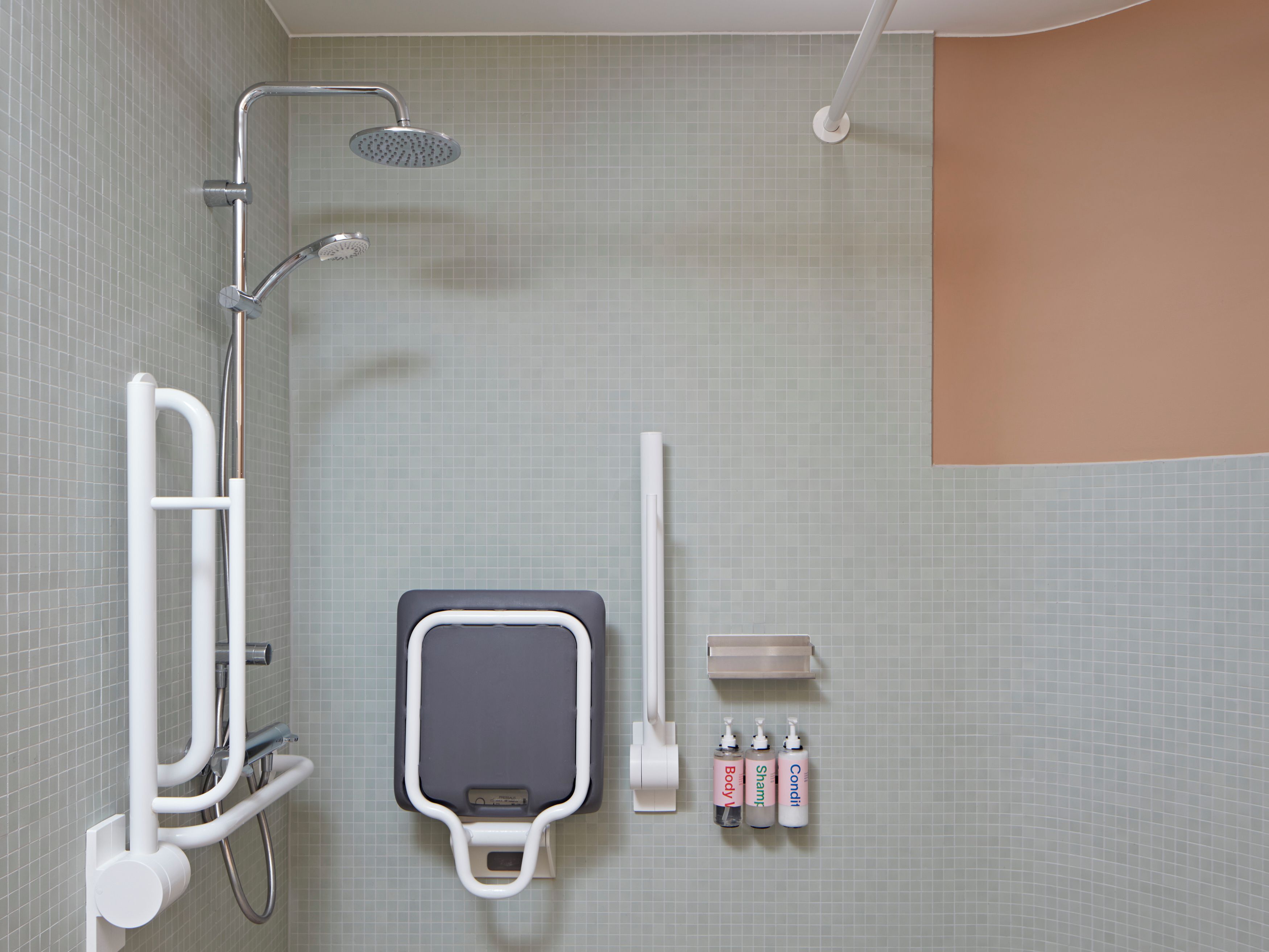 Un baño con ducha, inodoro y dispensador de gel antibacterial.