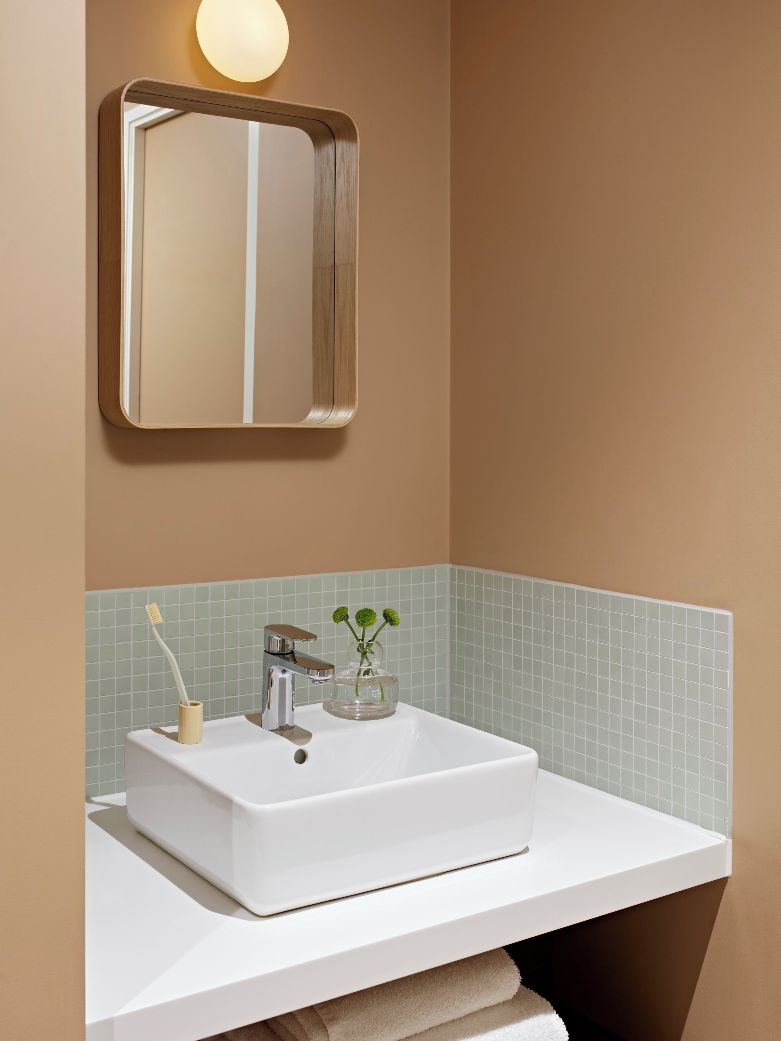 A bathroom with a white sink, a mirror, and a light fixture above it.