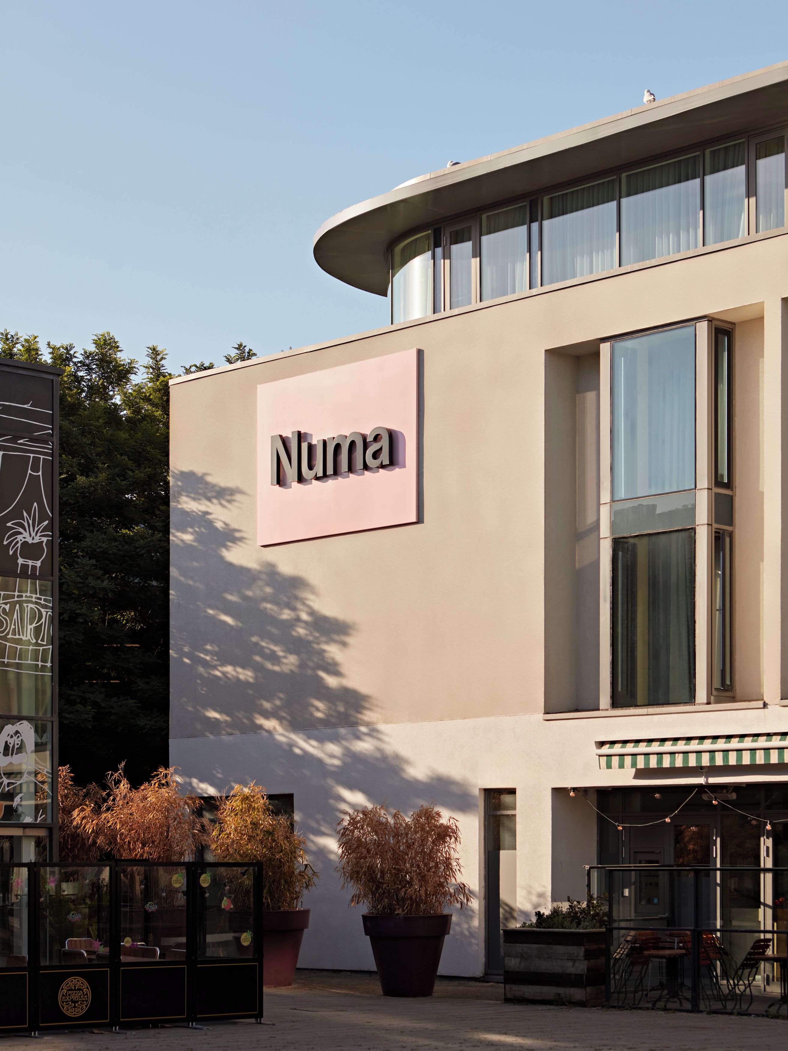 A building with a sign reading 'Numa' and a potted plant in front.