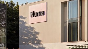 Un edificio con un letrero que dice 'Numa' y una planta en maceta al frente.