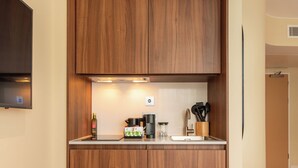 A compact kitchen with wooden cabinets, a built-in oven, and a coffee maker. - Numa Brighton Pavilion (Brighton)