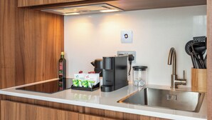 A modern kitchen with wooden cabinets, a stainless steel sink, a coffee maker, and tea packets. - Numa Brighton Pavilion (Brighton)