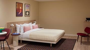 A modern hotel room with a bed, bedside tables, a desk, and a chair.
