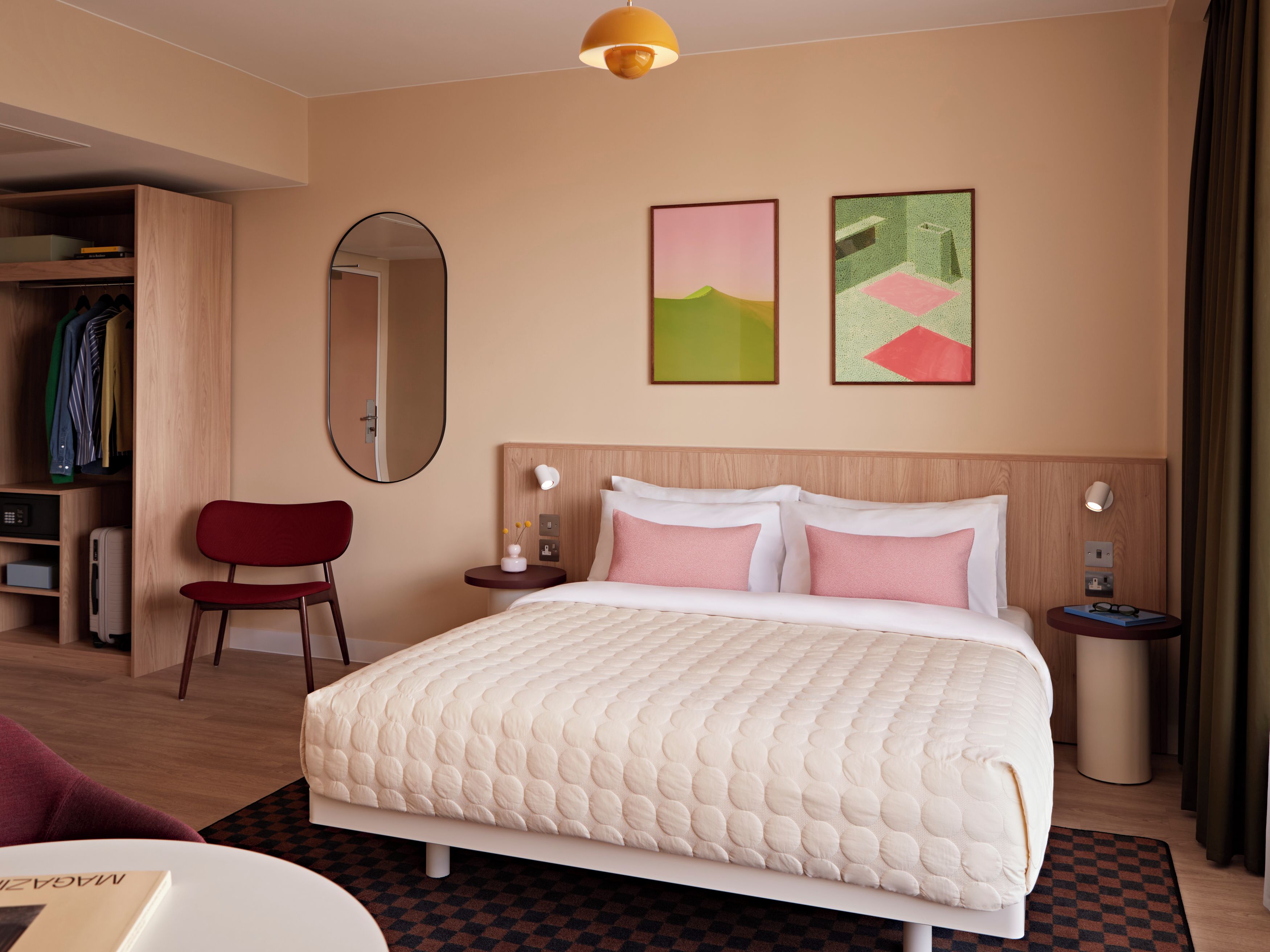 Una camera d'albergo con un letto, uno specchio, un armadio e opere d'arte alle pareti.