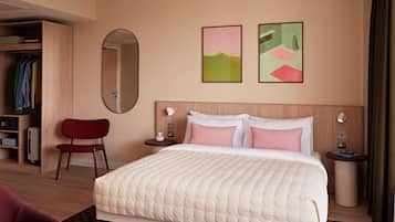 A hotel room with a bed, a mirror, a wardrobe, and artwork on the wall.