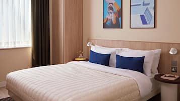 A hotel room with a bed, a nightstand, a lamp, a wardrobe, and two framed pictures on the wall.