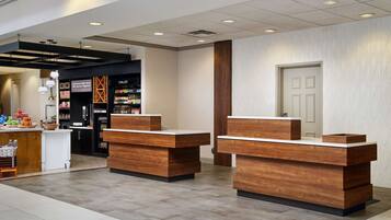 A modern reception area with wooden reception desks and a refrigerated beverage display.
