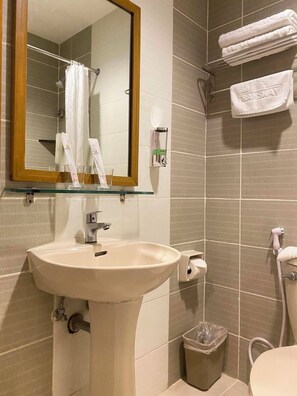 A bathroom with a sink, mirror, towel rack, and a trash bin. - Majestic Hotel (formerly Octagon Mansion Hotel) (Manila)